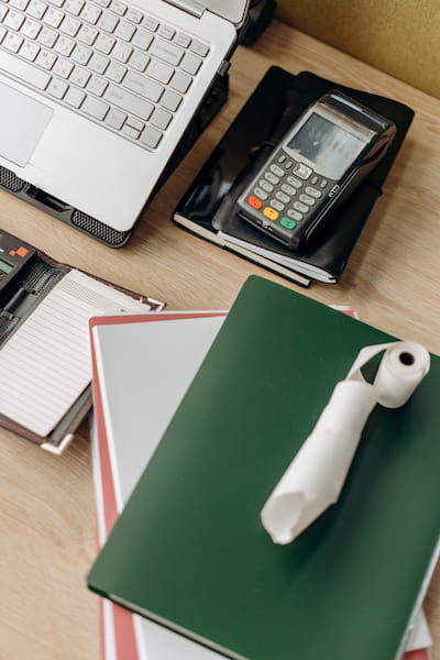 Mesa com alguns cadernos, calculadora e computador
